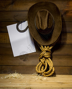 挂在旧木制牧场墙上的牛仔配件和文字空白背景图片
