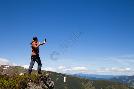 山顶上的人用手机拍自背景图片