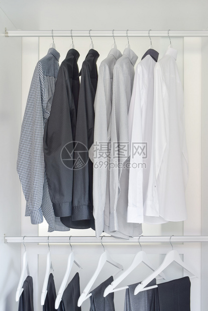 白色灰黑的衬衫和挂在木制衣柜的裤子图片