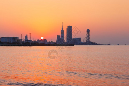 日落时现代巴统佐治亚阿贾拉从海滩到现代城市景色在美丽的日落时由Skyscrapersferris轮和字母塔观看格鲁吉亚巴统Adj图片