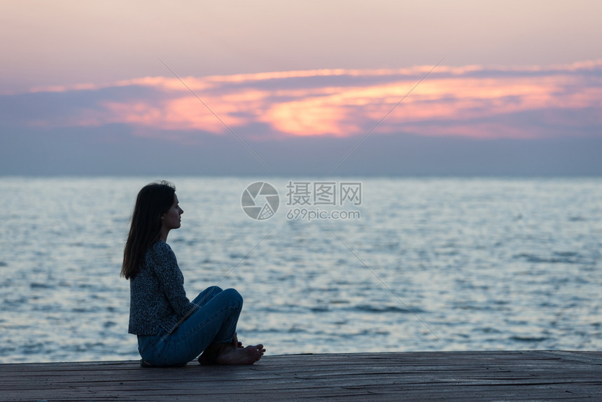 寂寞女孩坐在日出沙滩上女人在日出天空上摇欲坠图片