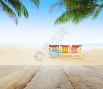浅海滩背景的木板桌顶椰子树下有海滩椅图片