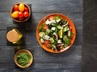 盘中的新鲜希腊沙拉和木制桌上的成分图片