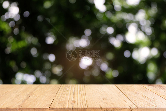 在户外花园灯光的抽象模糊背景前的黑木桌图像可以用于显示或装配您的产品图片