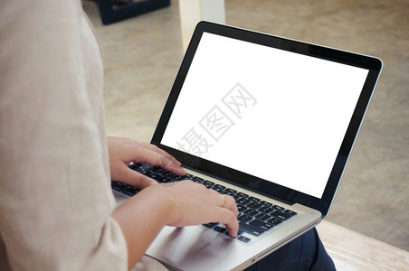 临时商业女在网上用笔记本电脑工作笔记本电脑在她家里的键盘上手动用笔记本电脑隔离屏幕图片