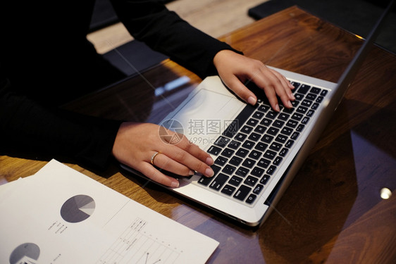 女人用笔记本电脑在木制桌上工作手打字在键盘上图片