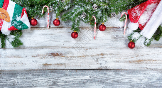 带有传统帽子红球装饰品和松果的雪圣诞圆形树枝以固定的形式在生锈木上图片