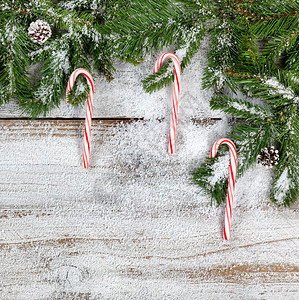 白雪圣诞树枝和糖果甘蔗以平整的固定形式在生锈的木上图片