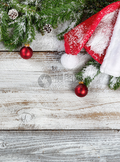 带有传统圣诞老人帽子和装饰品的雪状圣诞圆形树枝在生锈的木上以平整固定形式图片