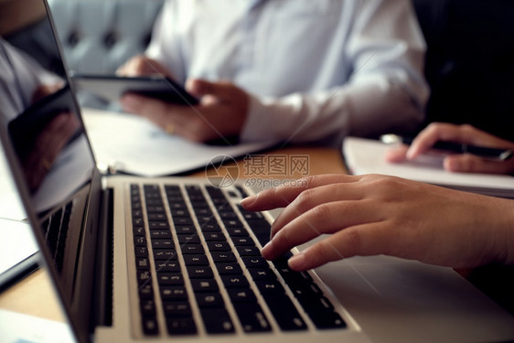 男人用笔记本电脑在木制桌上工作手打字在键盘上图片