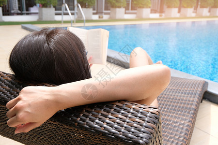 年轻的亚洲美女在游泳池里放松躺在温泉度假胜地的阳光休息室图片