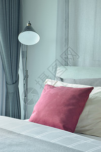 红天鹅绒枕头铺在床上旁有站着的灯图片