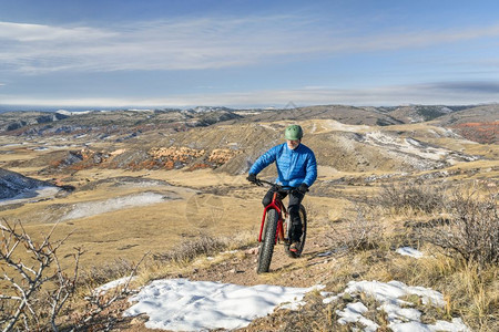 一名高级男骑着肥自行车一辆肥自行车骑在CheyenneRim的CheyenneRim在红山露天晚秋风景与一些雪图片