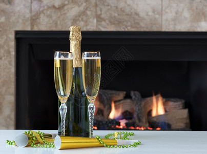 庆祝新年快乐配有金香槟和背景壁炉图片