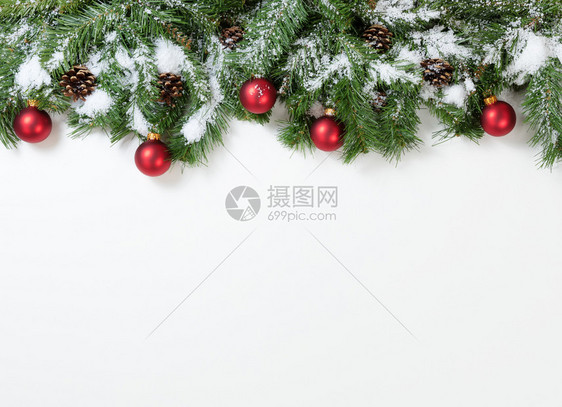 圣诞雪树枝和白色背景的红装饰品图片