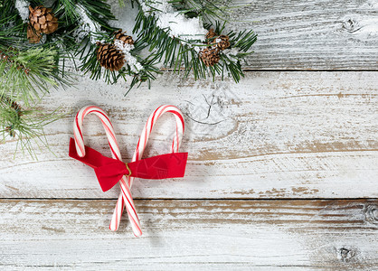 圣诞糖果甘蔗和弓粗糙的fir树枝生锈的白色木本底图片