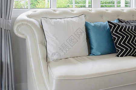 在古老起居室的白色皮革沙发上的白和蓝色枕头图片