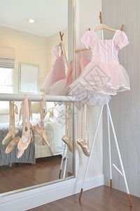 女孩粉红色裙子和芭蕾舞鞋挂在卧室的酒吧上图片
