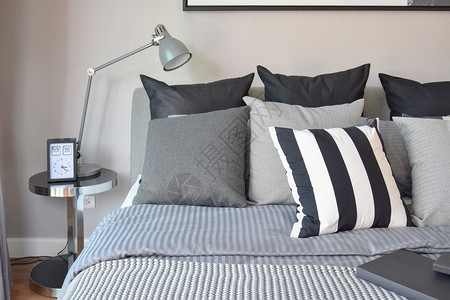 时髦的卧室内设计床边有黑色的枕头和装饰桌灯图片