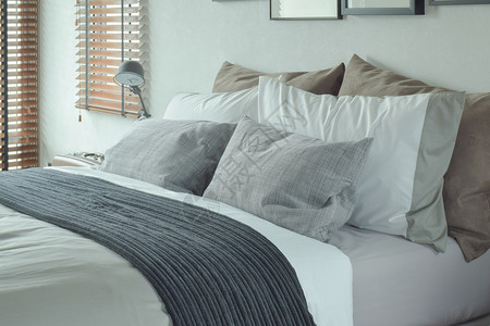 杂乱卧室深灰色床尾上有灰色和棕枕头背景