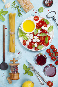 意大利食物背景莫扎雷拉奶酪新鲜的巴西叶番茄橄榄油意大利面条和红酒杯放在混凝土背景顶视线上图片