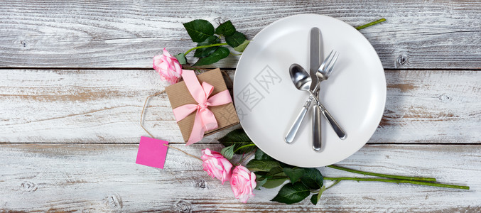 餐桌配有粉红玫瑰和礼品盒放在平面的生锈白木上图片