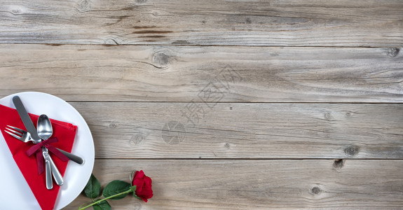 假日晚宴单红玫瑰和银器放在左下角生锈的木板上固定在平面图片