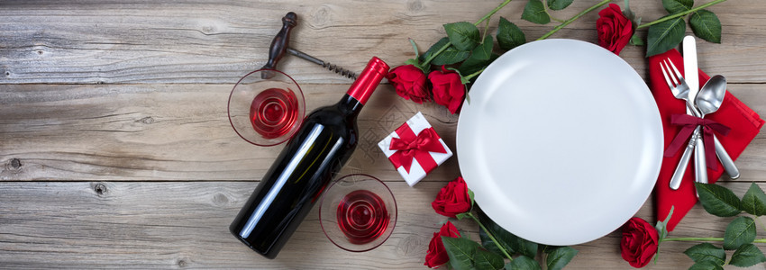 假日晚餐红酒和玫瑰生锈木上花玫瑰在平面露天图片