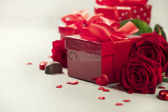 情人节日概念配红弓的礼物放在木制背景的情人节礼物盒上配有红色的履带弓挂在生锈背景上图片