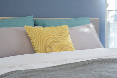 在现代室内卧铺在床上的黄色浅灰和绿枕头图片