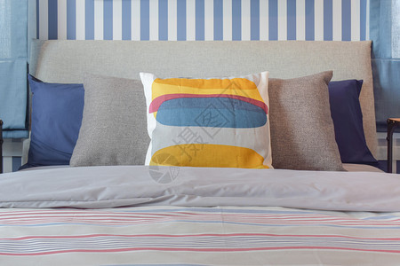黄色和蓝图形打印的枕头布置在条纹床上卧室图片