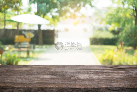 在户外花园灯光的抽象模糊背景前的木制桌子图像可以用于显示或装配您的产品图片