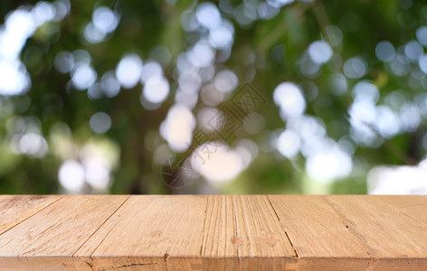在户外花园灯光的抽象模糊背景前的木制桌面图像可用于显示或装配您的产品图片