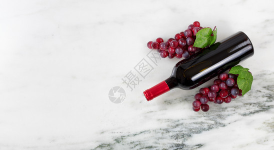 红色葡萄酒瓶和天然大理石架上的葡萄图片