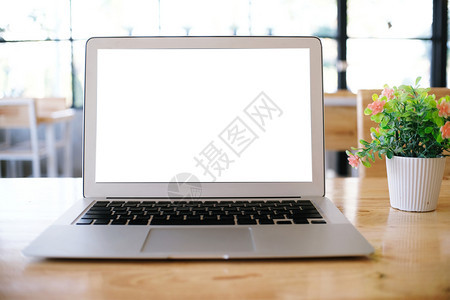 在咖啡厅空间前面的木桌上装空白屏幕的笔记本电脑用于文图片