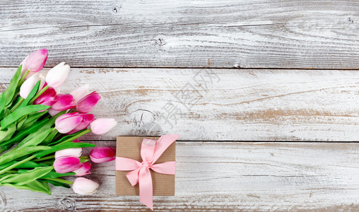 白风木板上的粉郁金香和棕色礼品盒图片