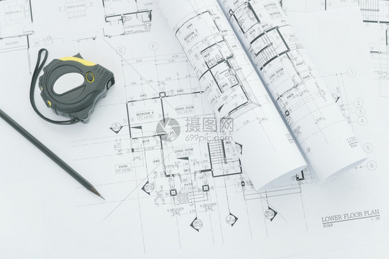 建筑师工作场所建筑蓝图上面有测量胶带安全头盔和桌面上的工具图片