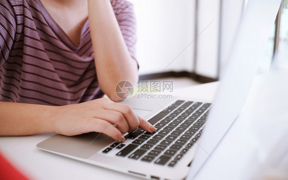 临时女商人在网上用笔记本电脑工作笔记本电脑在她家中的键盘上手孤立的屏幕上图片