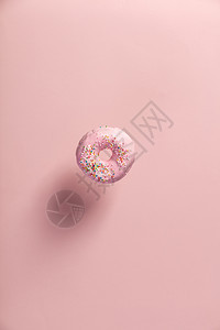粉红甜圈喷洒的落下或飞动与粉色糊面背景图片