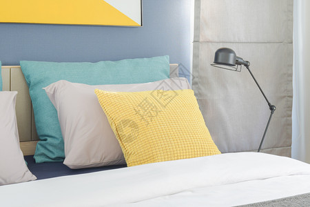 床上的黄色和绿枕头在现代室内卧的床桌边有黑色折叠灯图片