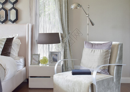 现代室内卧手椅和家用床边桌灯上有灰色枕头图片