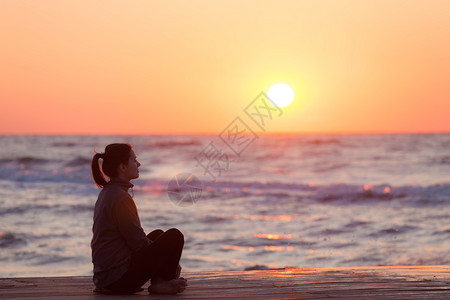 一个女人在日落时海滩观晒太阳的轮光图图片