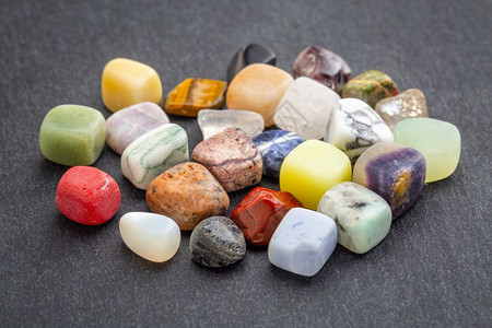 石块上有彩色宝一堆磨光的可贵多彩宝石与灰色块对立图片