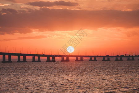 环绕着桥的太阳橙色日落海洋中赫里松阳光明媚的风景图片