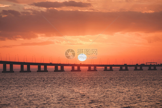 环绕着桥的太阳橙色日落海洋中赫里松阳光明媚的风景图片