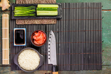 传统寿司成份大米鲑鱼肉姜黄瓜薯条酱汁和深色生锈背景的竹垫亚洲食物背景风平地传统寿司成份图片
