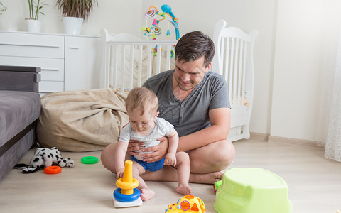 10个月大的婴儿男孩在卧室的地板上与父亲一起玩耍10个月大的婴儿男孩在卧室的地板上与父亲一起玩图片