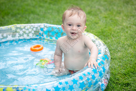 坐在花园的充气游泳池里坐在花园的充气游泳池里笑的男孩子坐在花园的充气游泳池里图片