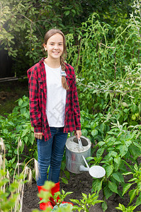 穿着橡皮靴的美丽笑少女在花园里工作穿着橡皮靴的笑少女在花园里工作图片