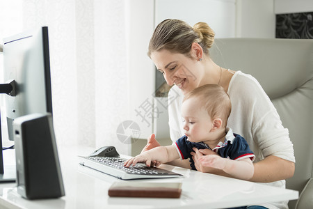 年轻母亲利用计算机和键盘打字来教她儿子的肖像母亲用计算机和键盘打字来教她儿子的肖像图片